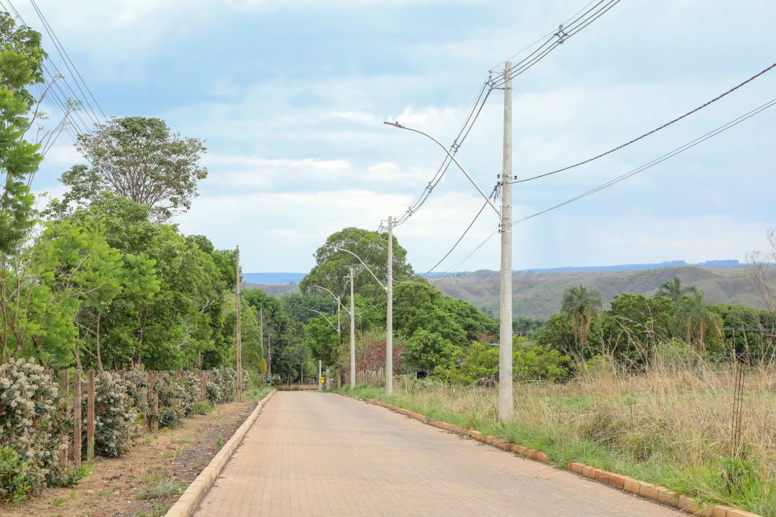 Estrada rural com postes de iluminação novos e mata dos dois lados, em Sobradinho dos Melos, no Paranoá