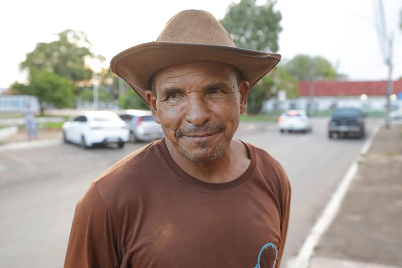 Antônio Ferreira Lima, de chapéu, na calçada da praça diante da avenida, em Planaltina