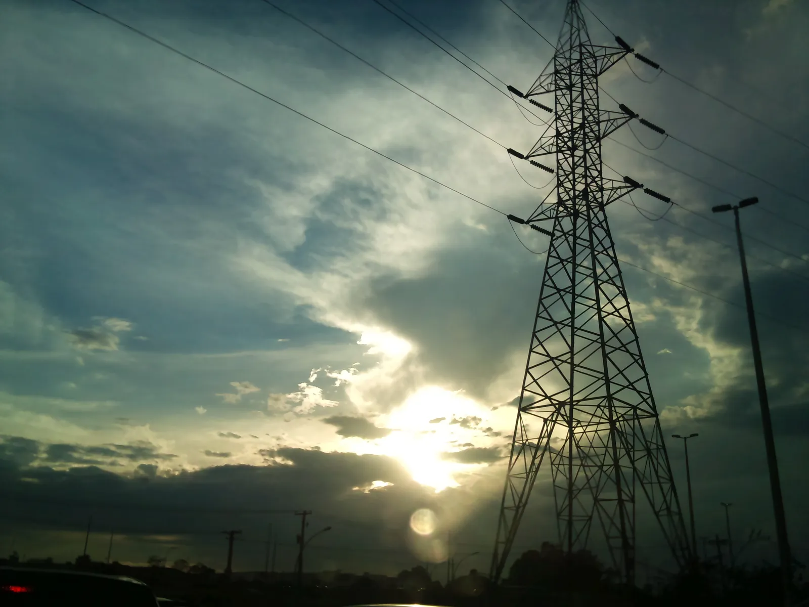 Postes e fios de energia ao entardecer, em área urbana do Distrito Federal
